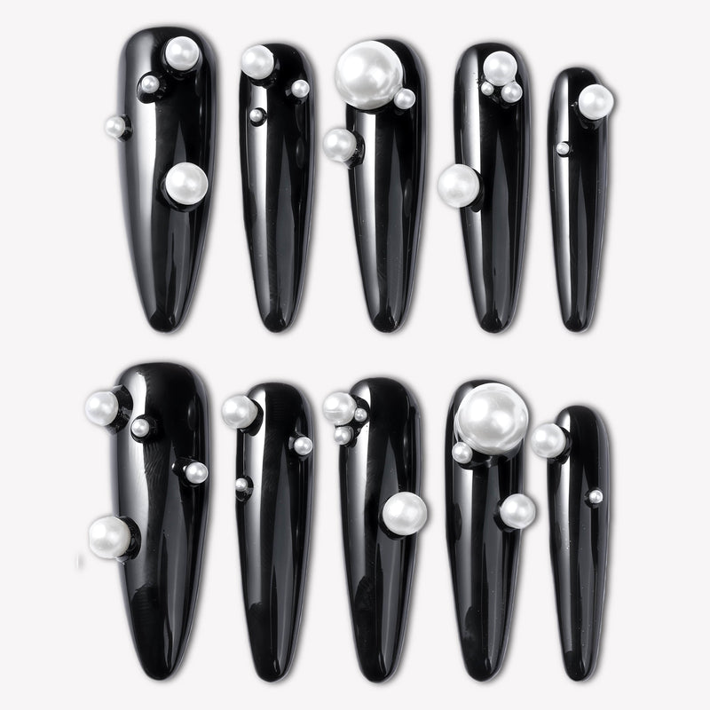 Flat lay of Louboutin Pearl Noir press-on nails with glossy black finish and pearl embellishments