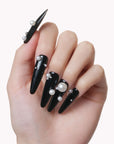 Hand model wearing Louboutin Pearl Noir press-on nails with glossy black finish and pearl embellishments
