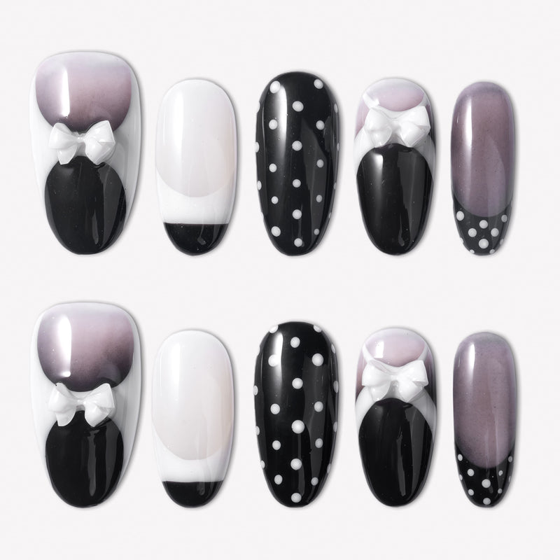 Flat lay of black and white press-on nails with polka dots, glossy finishes, and white bow accents
