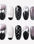 Flat lay of black and white press-on nails with polka dots, glossy finishes, and white bow accents