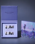 Packaging display of black and white press-on nails with polka dots and white bow accents in a lavender box