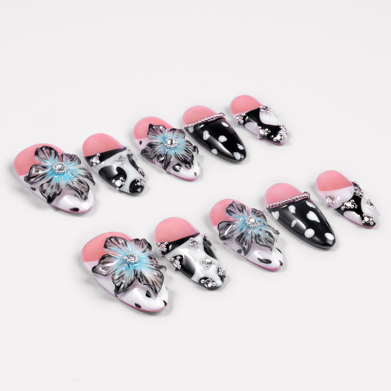 Angled flat lay of Midnight Bloom pink, navy and white press-on nails with blue flowers, polka dots and rhinestones