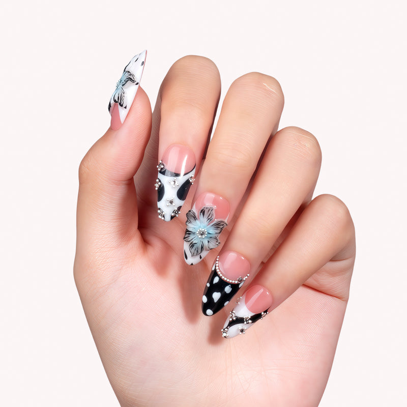 Studio hand close-up wearing Midnight Bloom pink and navy press-on nails with blue flowers, white dots and rhinestones