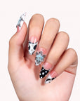 Studio hand close-up wearing Midnight Bloom pink and navy press-on nails with blue flowers, white dots and rhinestones