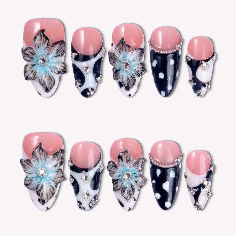 Midnight Bloom pink and navy press-on nails with blue floral charms, white dots and rhinestone accents in a flat lay