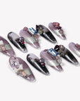 Flat lay of Mineral Dreamscape press-on nails arranged diagonally with lilac, black, silver, and gemstone accents