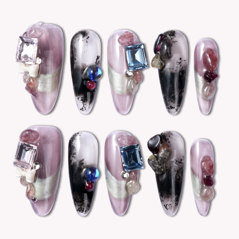 Flat lay of Mineral Dreamscape press-on nails with lilac, black, and silver tones, finished with gemstone accents