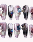 Flat lay of Mineral Dreamscape press-on nails with lilac, black, and silver tones, finished with gemstone accents
