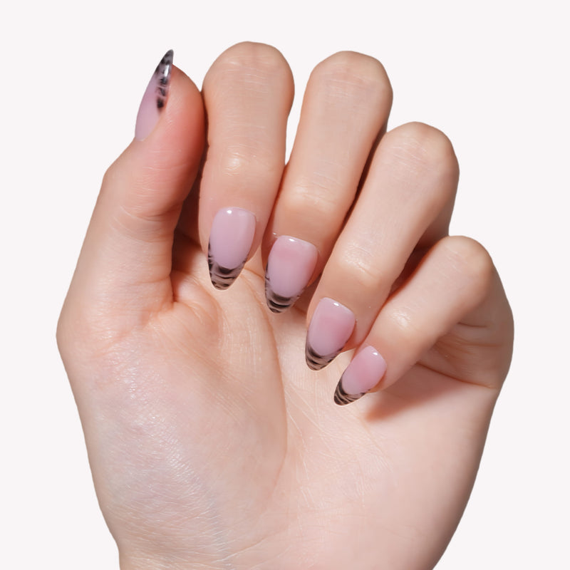 Close-up of a hand model wearing Mist Fade press-on nails in nude gray with soft white smoky tips