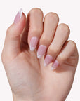 Hand model wearing Mist Fade press-on nails in nude gray with soft white smoky tips