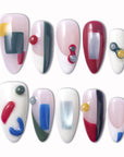 Modernist Dream press-on nails with abstract geometric color blocks, red blue yellow gray accents, raised round details, and glossy nude white bases