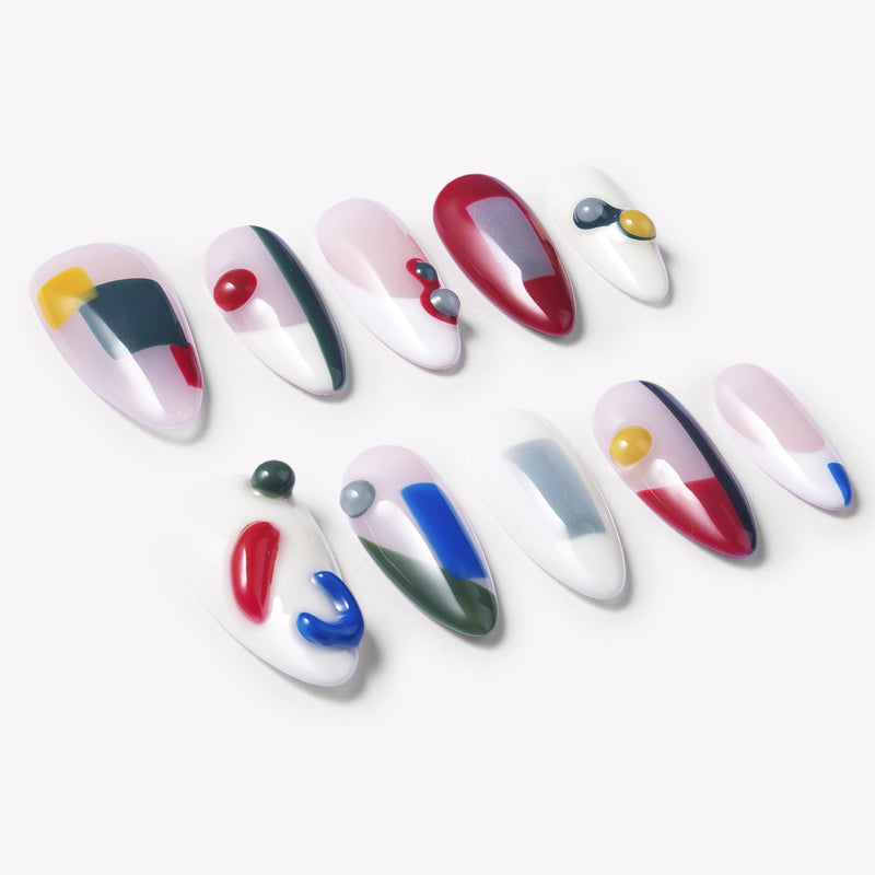 Flat lay of Modernist Dream press-on nails with abstract red blue yellow green color blocks, raised round accents, and glossy nude white bases