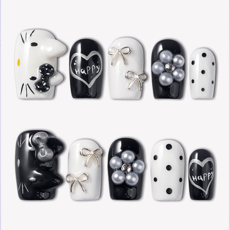 Monochrome Meow press-on nails with black and white cat designs, silver bow accents, pearl charms, polka dots, and happy heart lettering