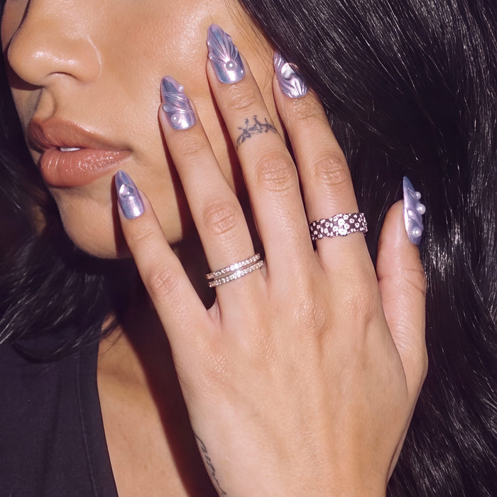 Model wearing Moonwave blue purple iridescent press-on nails with pearl accents beside her face
