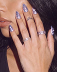 Model wearing Moonwave blue purple iridescent press-on nails with pearl accents beside her face