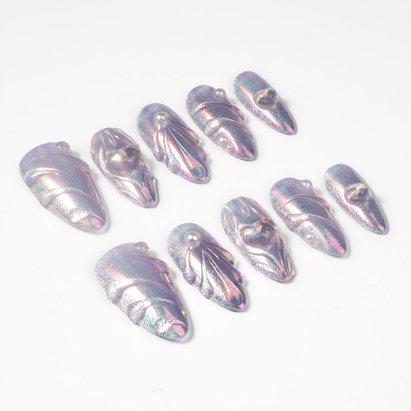 Angled flat lay of Moonwave iridescent shell press-on nails with raised wave lines and pearl accents