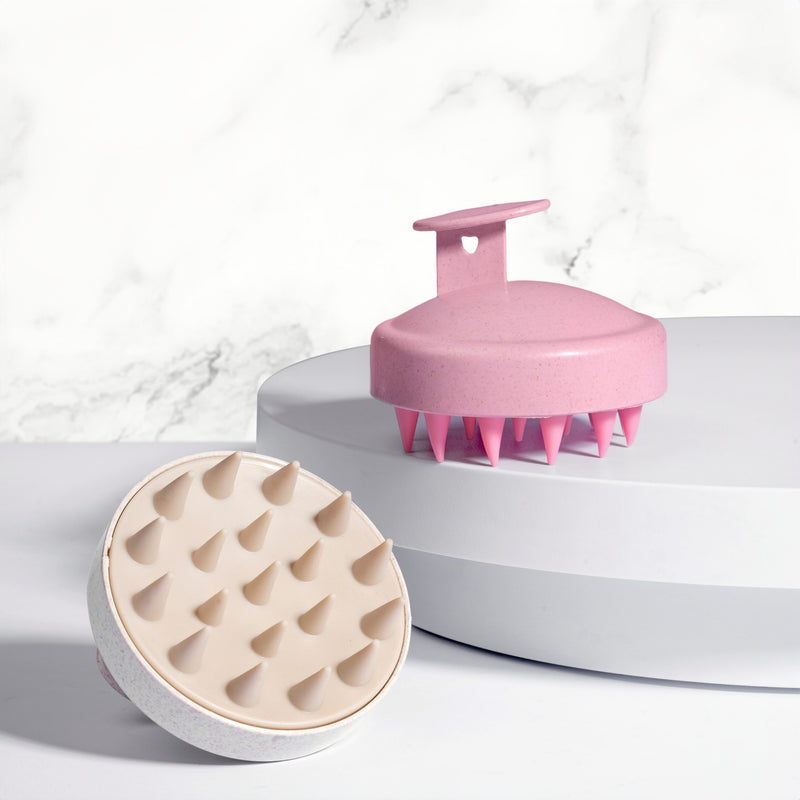 Pink and cream nail-friendly scalp massager brushes with flexible silicone tips displayed on white pedestals