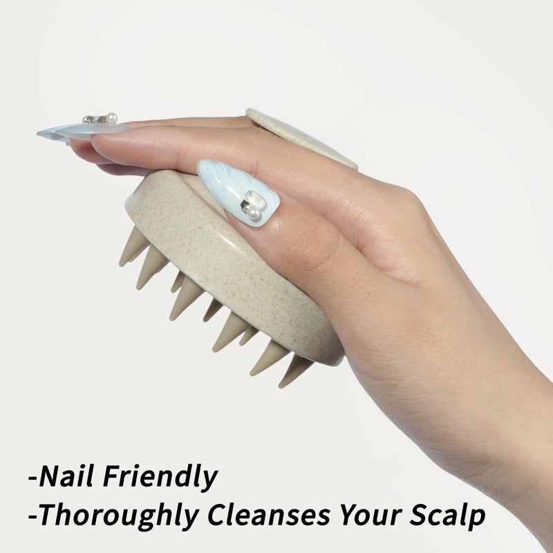 Hand with long decorated nails gripping the cream nail-friendly scalp massager brush for comfortable cleansing