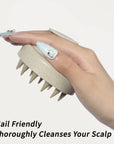 Hand with long decorated nails gripping the cream nail-friendly scalp massager brush for comfortable cleansing