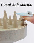Close-up of cloud-soft cream silicone tips on the nail-friendly scalp massager beside a long blue jeweled nail