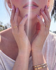 Nebula Kiss purple cat-eye almond press-on nails with pink heart accents shown on an outdoor model in sunlight