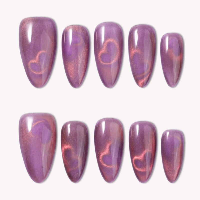 Nebula Kiss purple and pink cat-eye press-on nails with glowing heart accents arranged in a white flat lay