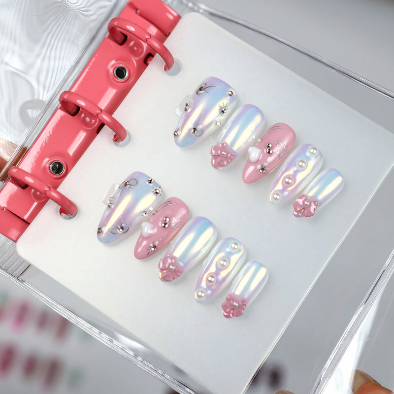 9 to 9 Chic pink and blue iridescent press-on nails with bows, pearls and stars displayed in a binder