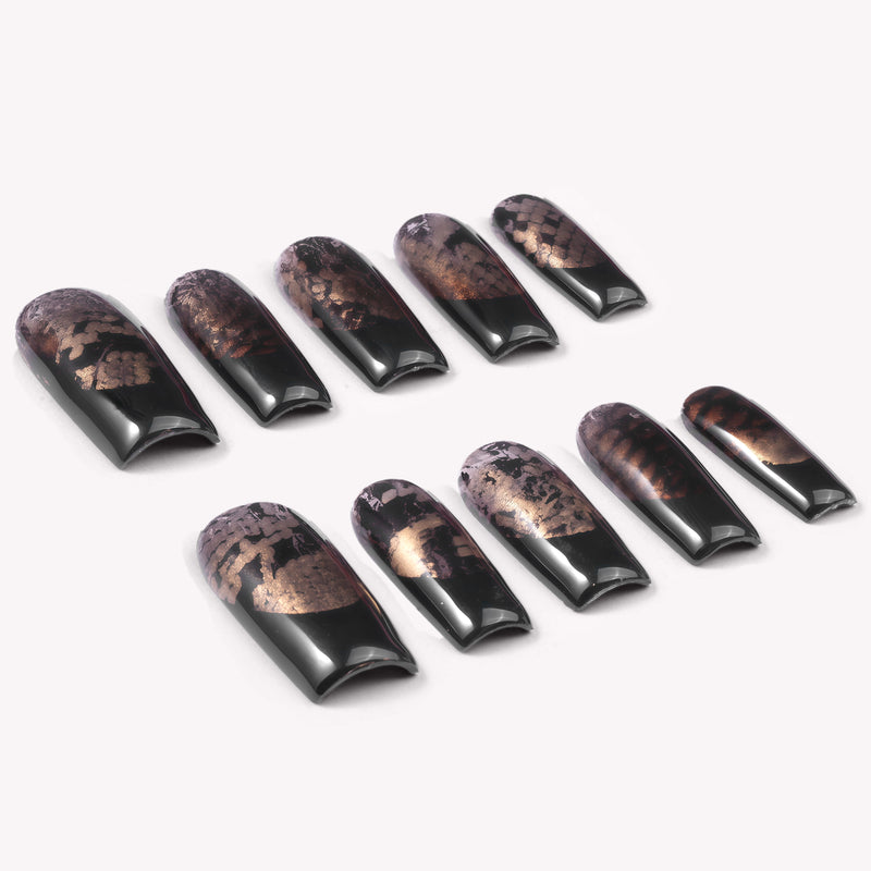 Nocturne Gild press-on nails in glossy black with metallic gold foil accents arranged in a flat lay on a white background