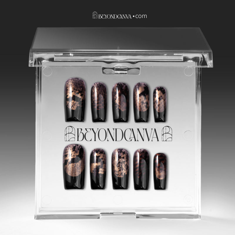 Nocturne Gild press-on nails in glossy black with metallic gold foil accents displayed in a clear packaging box