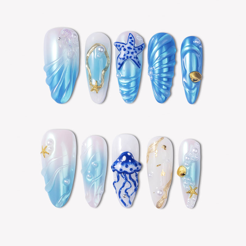Ocean Rhapsody blue and pearl press-on nails with starfish, shell, jellyfish and wave details in a flat lay