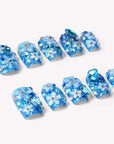 Flat lay of blue Ocean Sparkle Bloom handmade press-on nails with floral accents, crystals, and silver beads.