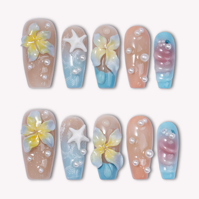 A set of beach-inspired press-on nails with yellow flowers, starfish accents, and pearl details on a white background
