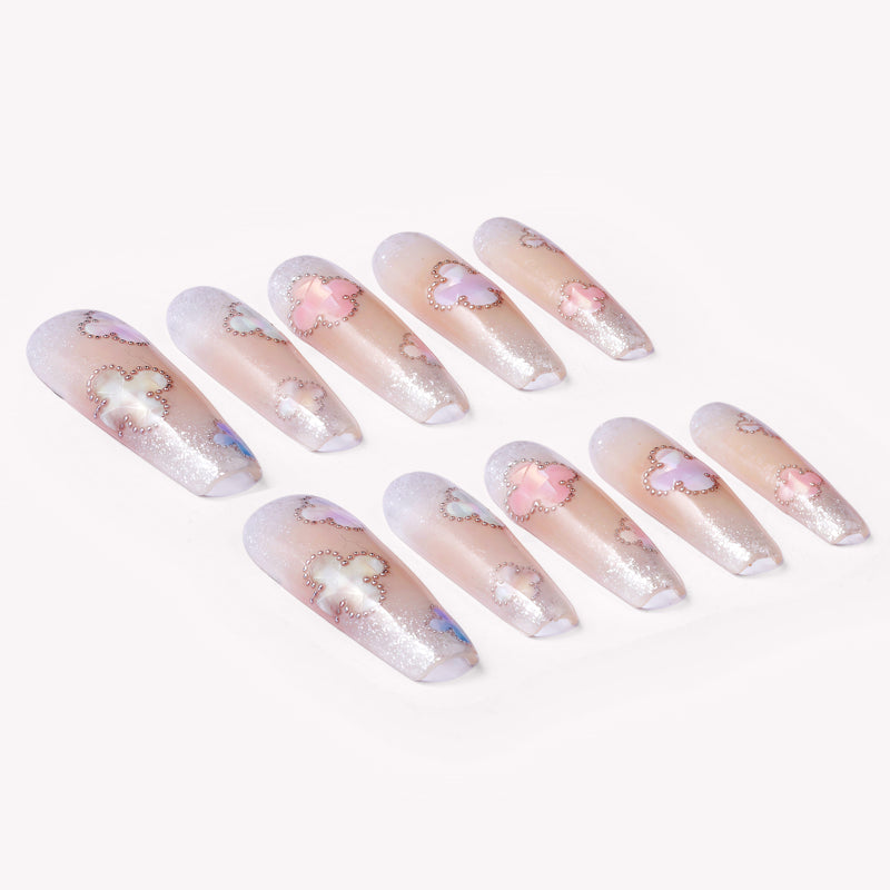 Opal Whisper press-on nails in pale pink and clear shimmer with white flower accents arranged on a white background