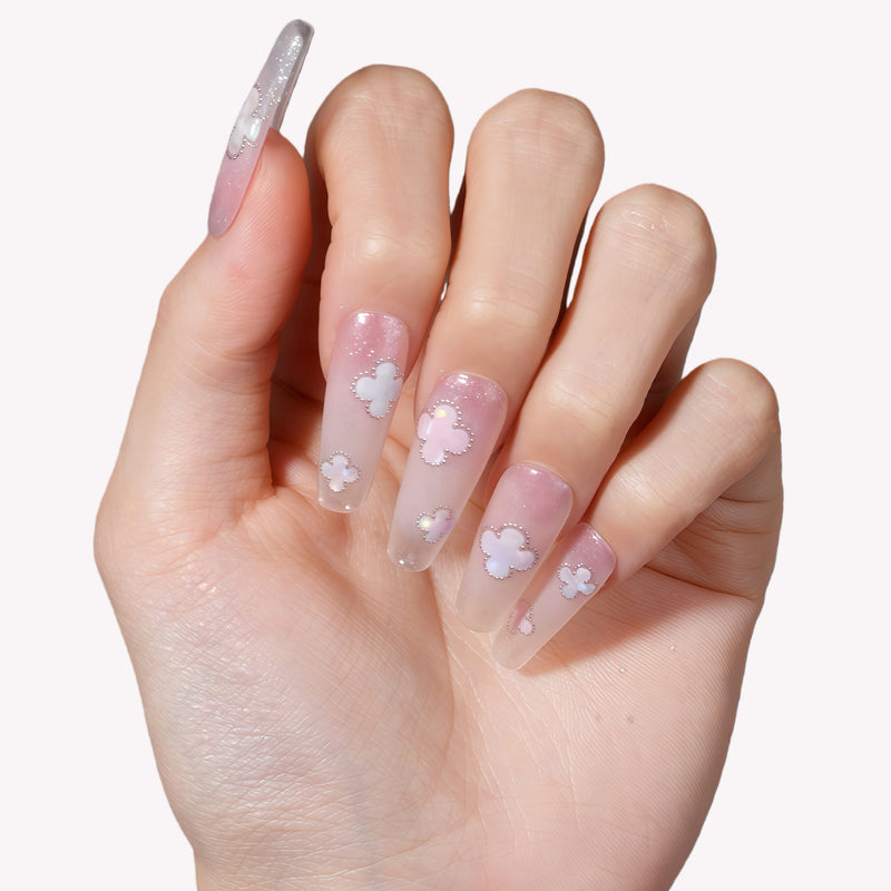 Hand model wearing Opal Whisper press-on nails in pale pink and clear shimmer with white flower accents