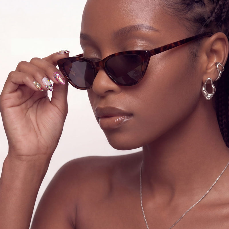 Lifestyle portrait of a hand model wearing Opulent Ribbon Reverie press-on nails while adjusting sunglasses