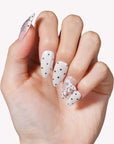 Close-up of a hand model wearing Parisian Polka press-on nails in ivory and blush with black polka dots and pearl accents