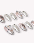 Parisian Polka press-on nail set in ivory and blush with black polka dots and pearl chain accents arranged in a flat lay on a white background