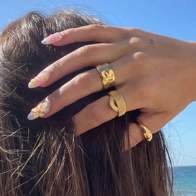 Beach hand close-up wearing Pastel Bloom raised floral press-on nails with yellow blossoms and gold rings
