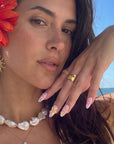 Beach portrait of a model wearing Pastel Bloom pink and yellow floral press-on nails with gold rings