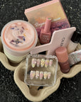 Pastel Bloom press-on nail set displayed with pink beauty products, a mirror and drink carrier