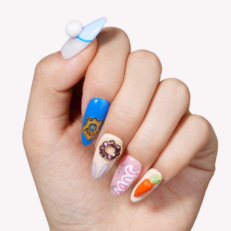Hand model wearing cartoon-themed press-on nails with blue, white, pink, and orange character-inspired accents