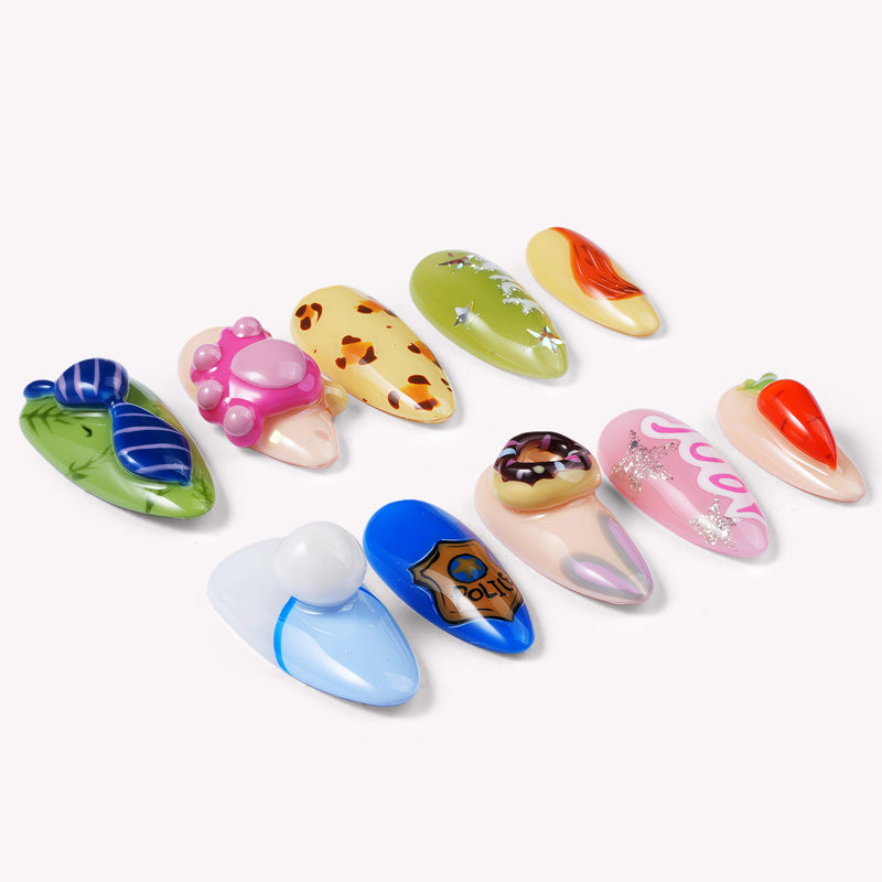 Flat lay of cartoon-themed press-on nails with blue, green, pink, yellow, and orange character-inspired accents
