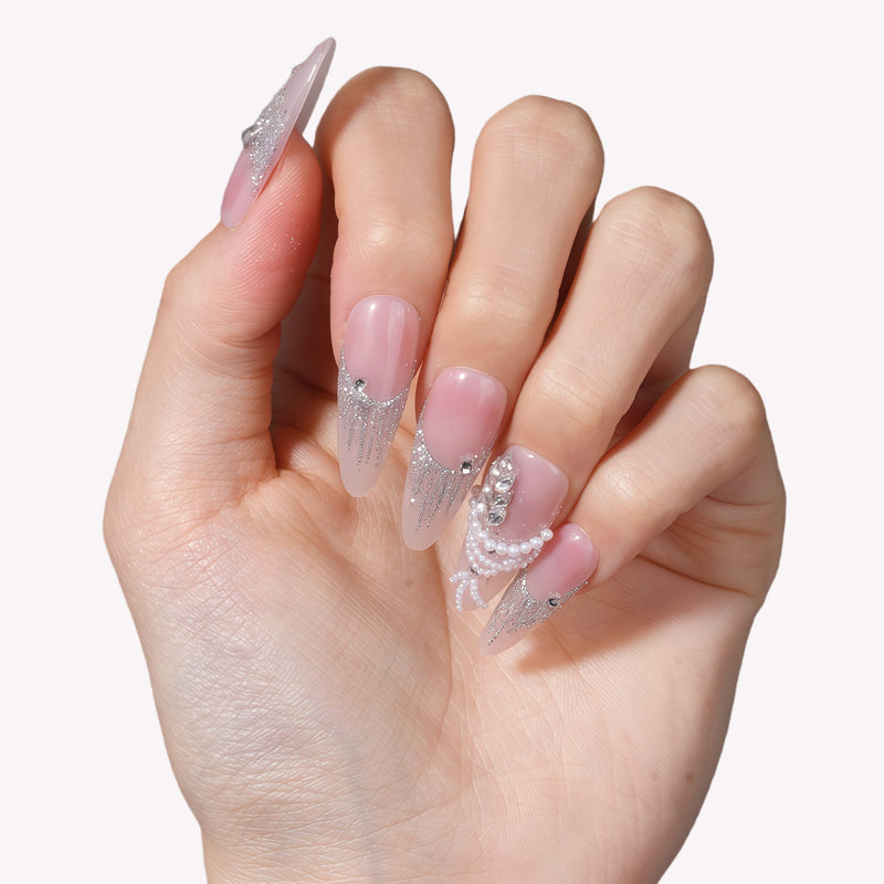 Hand model wearing Pearl Cascade press-on nails in nude pink with silver glitter tips and pearl accents