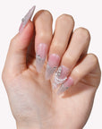 Hand model wearing Pearl Cascade press-on nails in nude pink with silver glitter tips and pearl accents