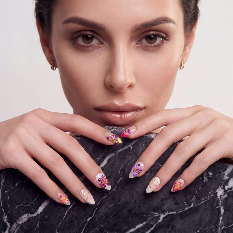 Model displaying Petal Poem colorful floral press-on nails with both hands resting on black marble