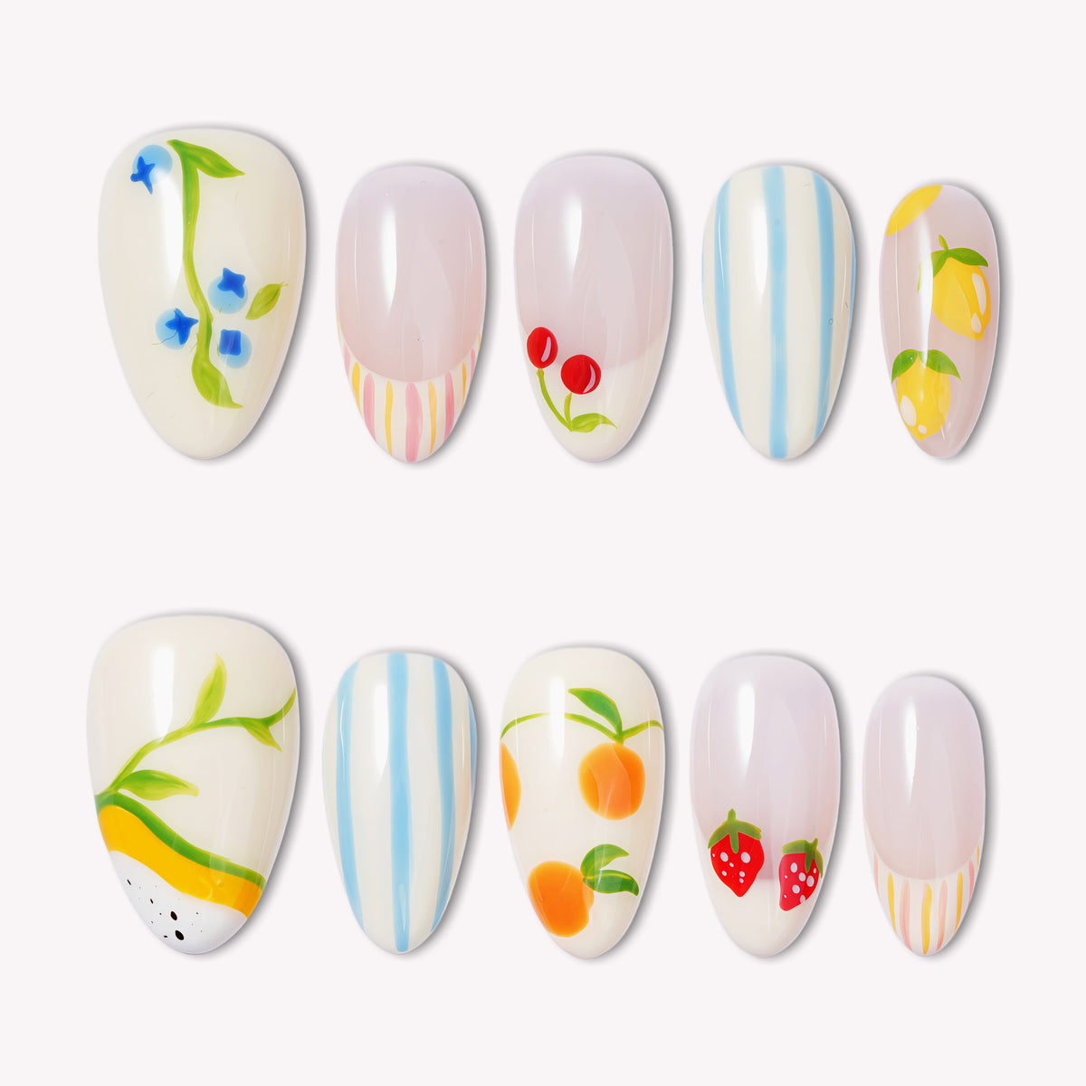 Set of handmade press-on nails with fruit and floral designs, blue stripes, and pastel accents on a white flat lay.