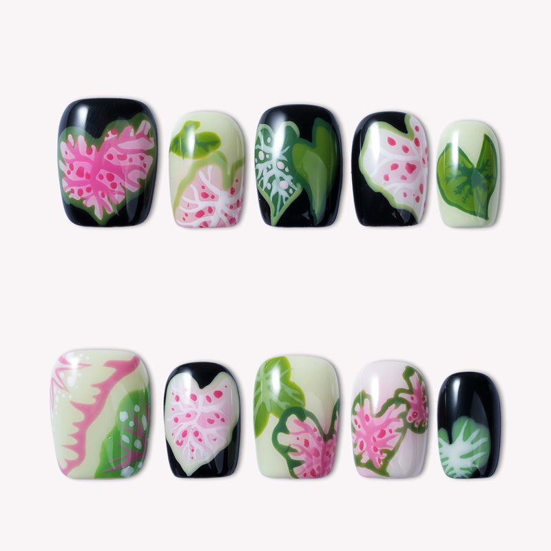 Pink Caladium press-on nails arranged in a flat lay with black, pink, green, and cream leaf-inspired floral designs