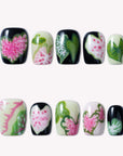 Pink Caladium press-on nails arranged in a flat lay with black, pink, green, and cream leaf-inspired floral designs