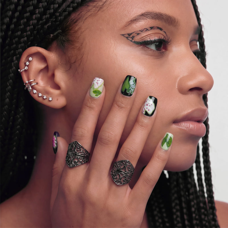Portrait of a hand model wearing Pink Caladium press-on nails with black, pink, and green leaf-inspired floral art