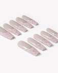 Flat lay of Pink Confetti press-on nails with sheer nude pink bases and sparkling pink silver glitter French tips